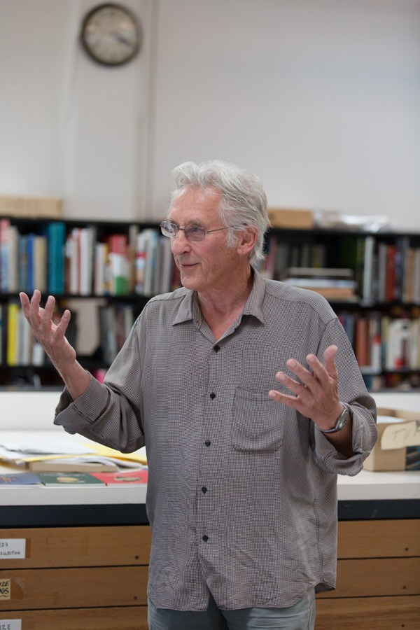Artist Ed Ruscha gestures while speaking in his Culver City studio, with bookshelves and a wall clock visible behind him.
