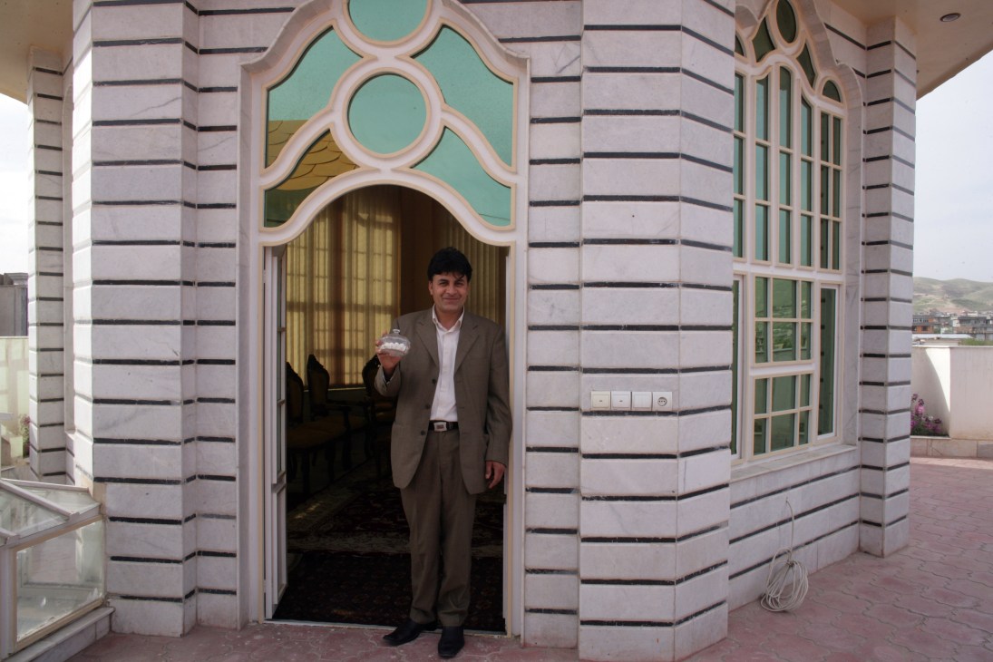 Mohammad Zaher Faqiry holds a Pyrex sugar bowl in a decorative turquoise and pink pavilion on his mansion's roof.