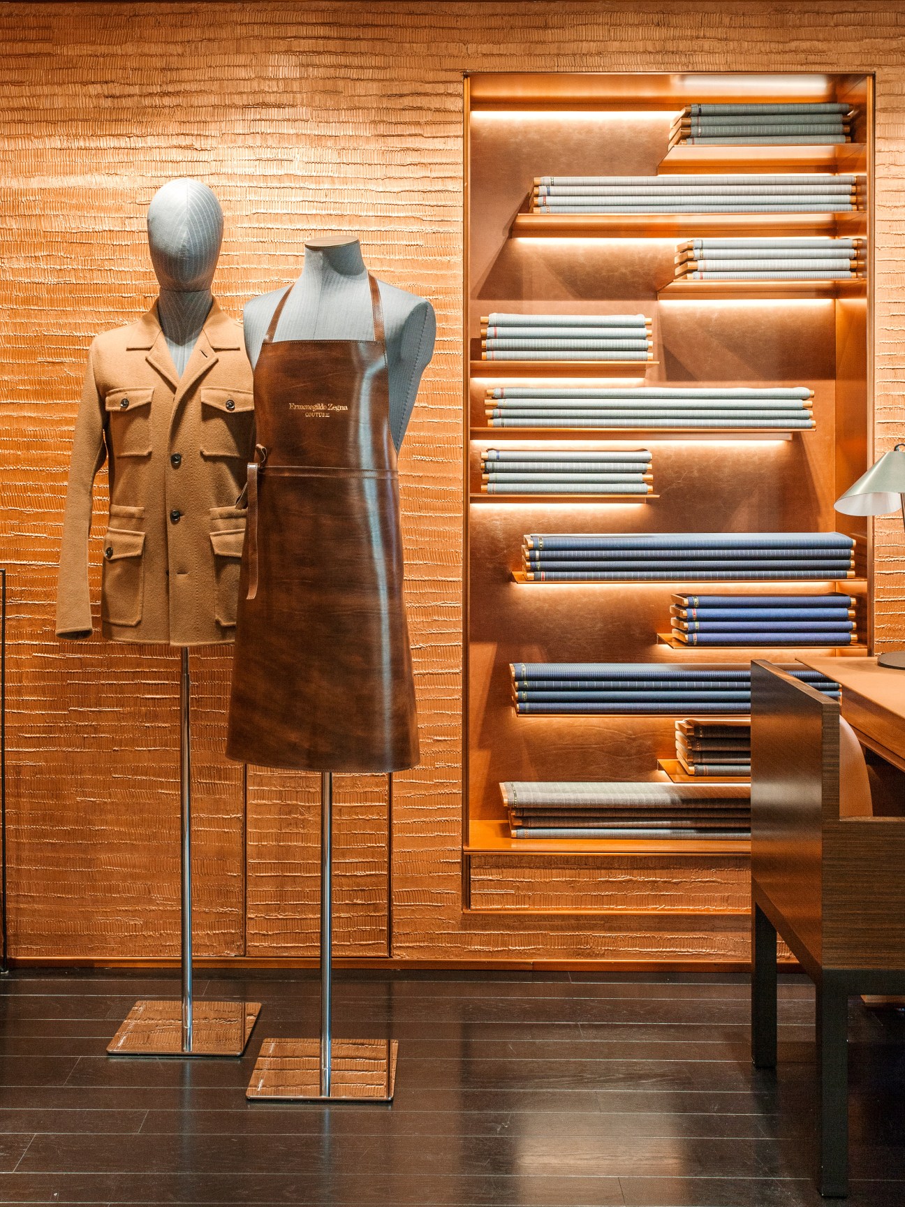 Zegna flagship store display featuring tailored jackets on mannequins with honeyed rosewood shelving showcasing fabric samples.