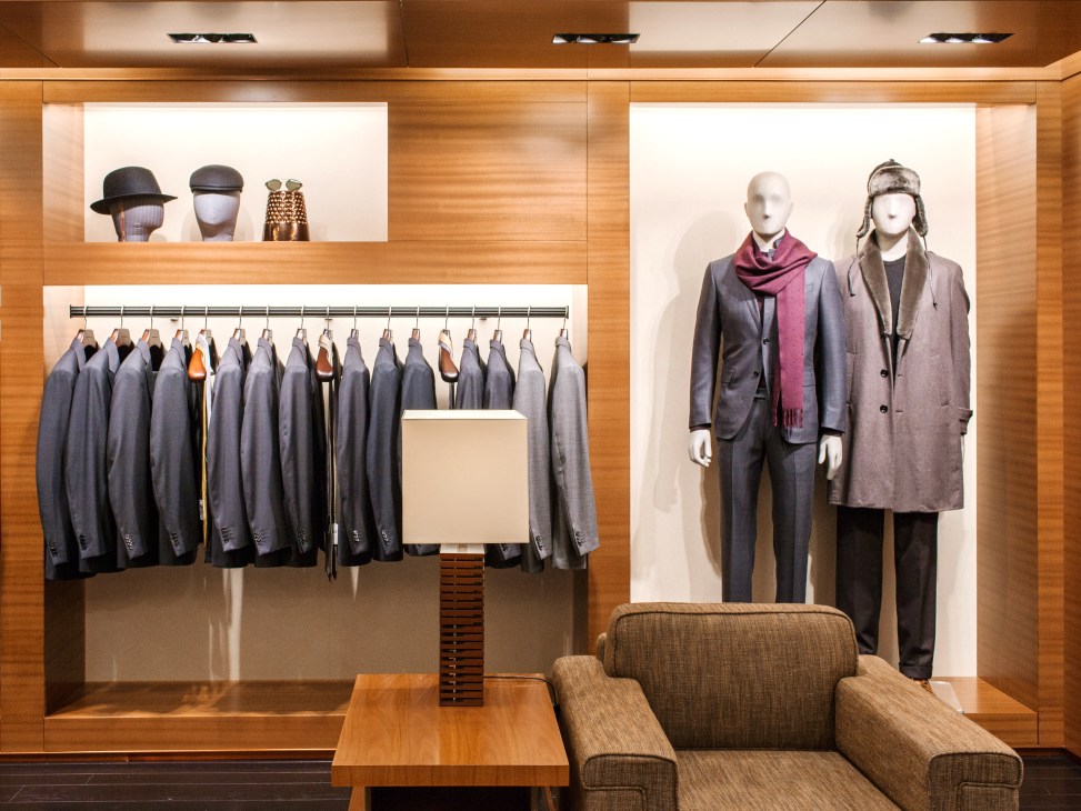 Interior of Zegna London flagship with tailored suits on display and mannequins wearing menswear.