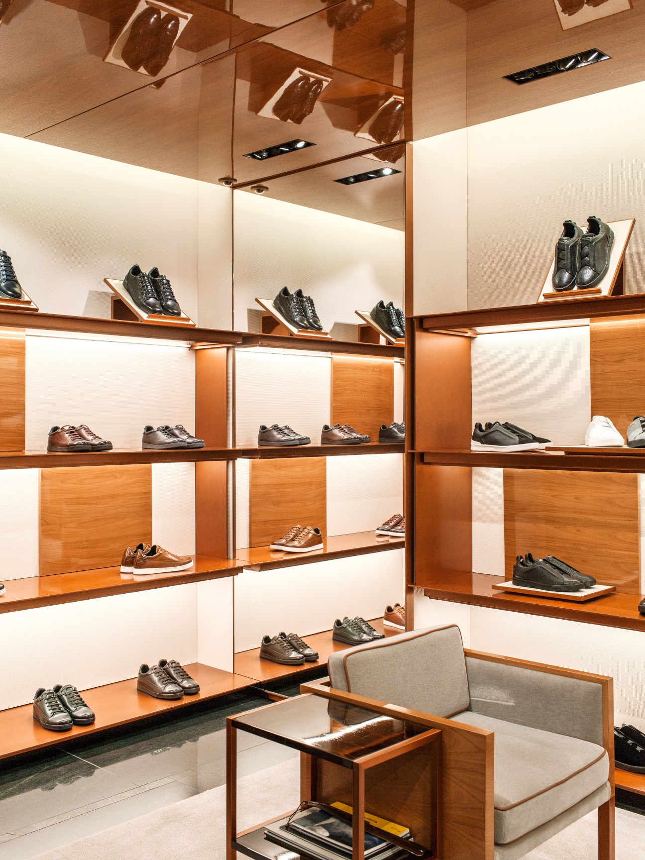 Zegna London flagship shoe display with honeyed rosewood shelves and dark Italian marble floors.