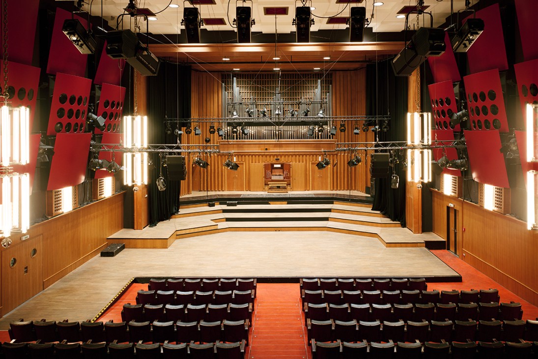 Concert hall with tiered seating, wooden panels, and large pipe organ at the back of the stage